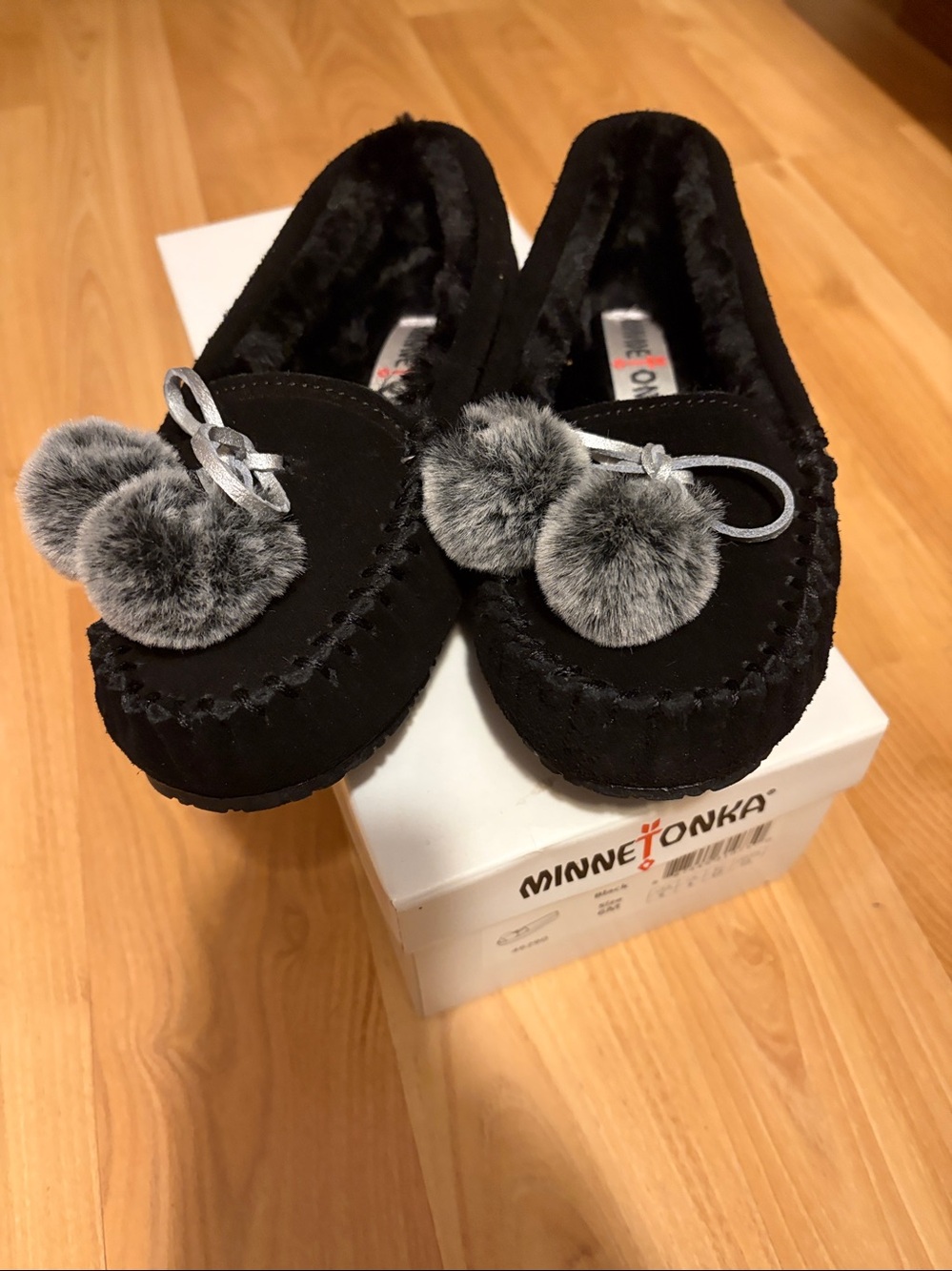 New in box Minnetonka Womens Black Moccasins with Gray Faux-Fur Poms